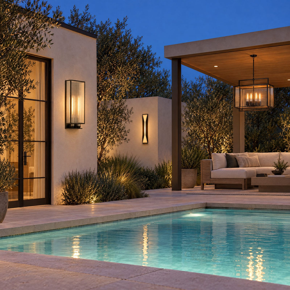 Shop the look: Modern pool terrace at dusk with ribbed-glass bronze sconces flanking a plaster pool house, frosted-glass sconces on the garden wall, and an iron hanging lantern in the cabana