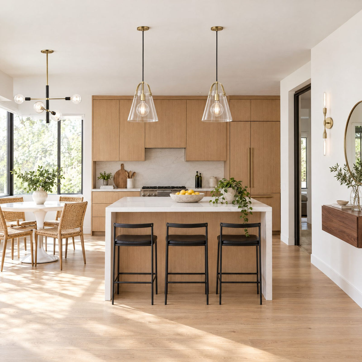 Shop the look: Modern kitchen with two Mitzi Karin aged brass pendants over the island, a Mitzi Astrid chandelier over the breakfast table, and a Tara brass wall sconce by the console